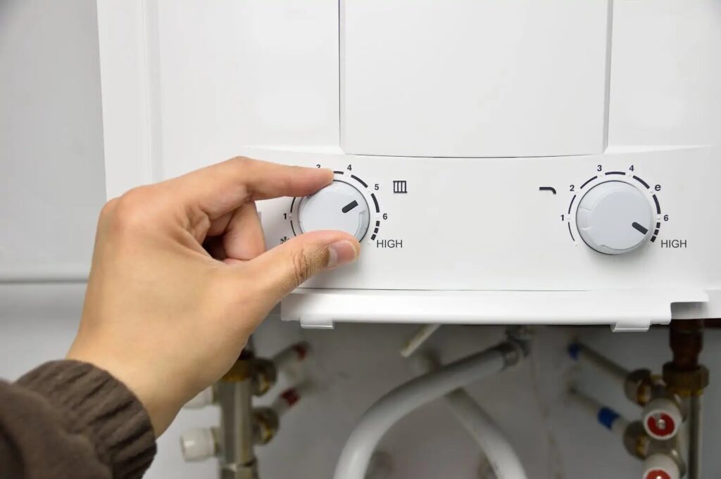 Hand adjusting the temperature knob on an electric tankless water heater