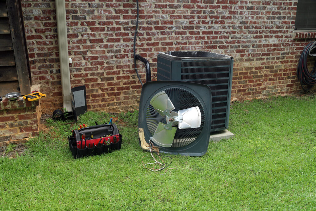 Air Conditioning unit outside a brick home being worked on, toolbox next to the unit. 